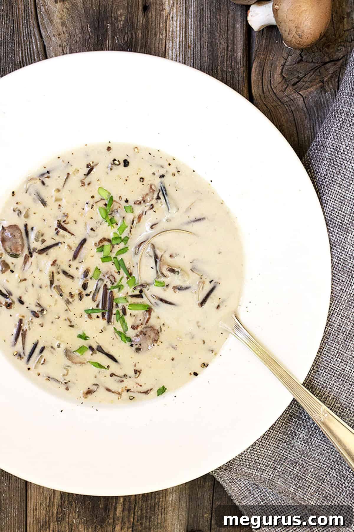 Close-up shot of creamy wild rice and mushroom soup in a rustic white bowl, showcasing its rich texture and hearty ingredients.