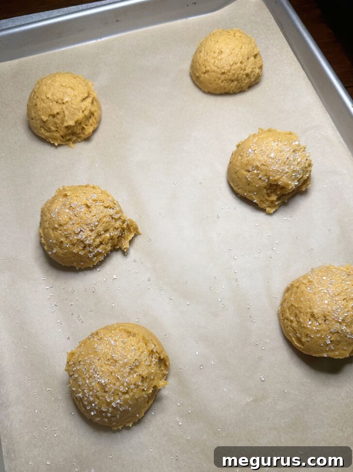scoops of pumpkin cookie dough on baking sheet sprinkled with sugar before baking