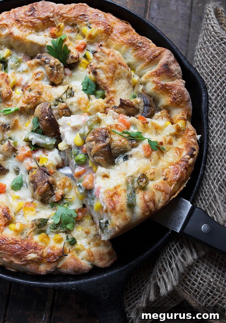 Close-up of skillet turkey pot pie pizza, highlighting the rich filling and golden crust.