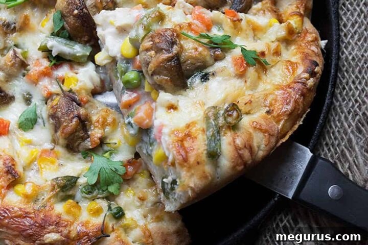 Close-up of deep-dish turkey pot pie pizza with a slice removed, showing the creamy filling.