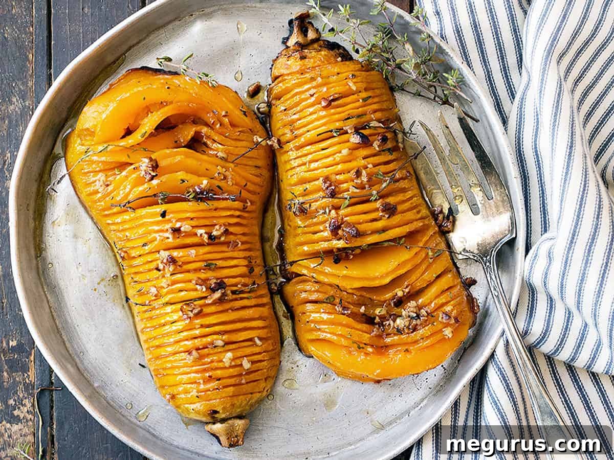 Hasselback butternut squash on a serving platter with a fork, showing the beautiful roasted slices and glaze