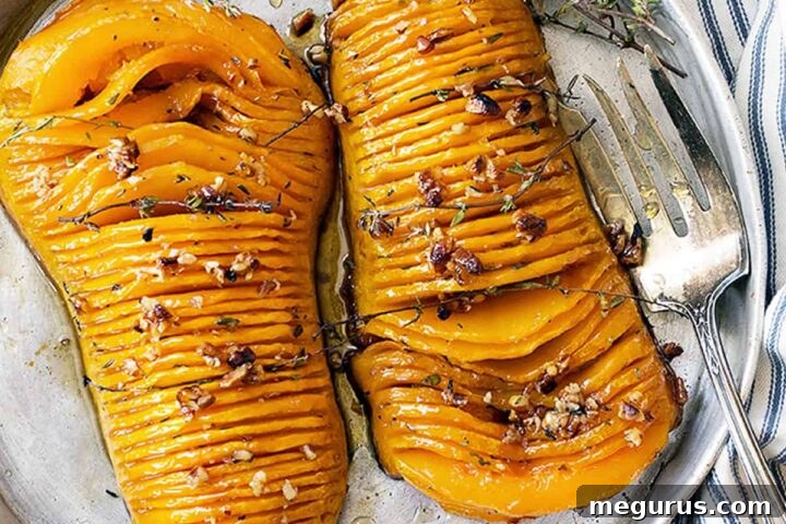 Hasselback butternut squash on a serving platter with a fork, showing the beautiful roasted slices and glaze