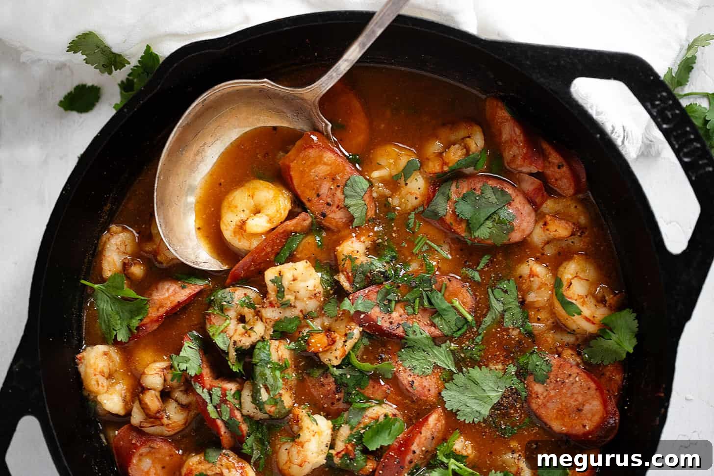Spicy chorizo and shrimp served in a cast iron skillet with a wooden spoon, ready to be enjoyed.