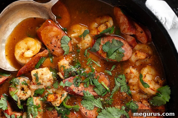 Spicy chorizo and shrimp in a cast iron skillet with spoon.