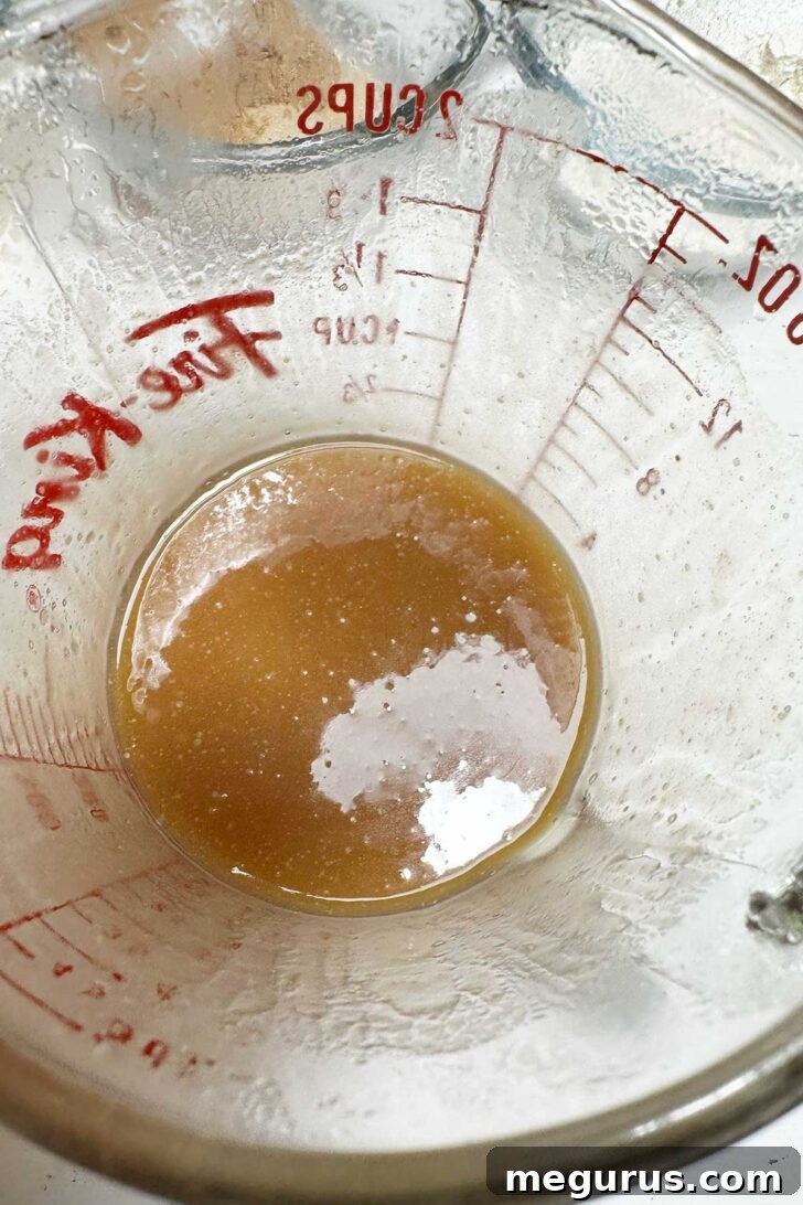 Finished sticky toffee sauce poured into a measuring cup, showcasing its rich, thick consistency