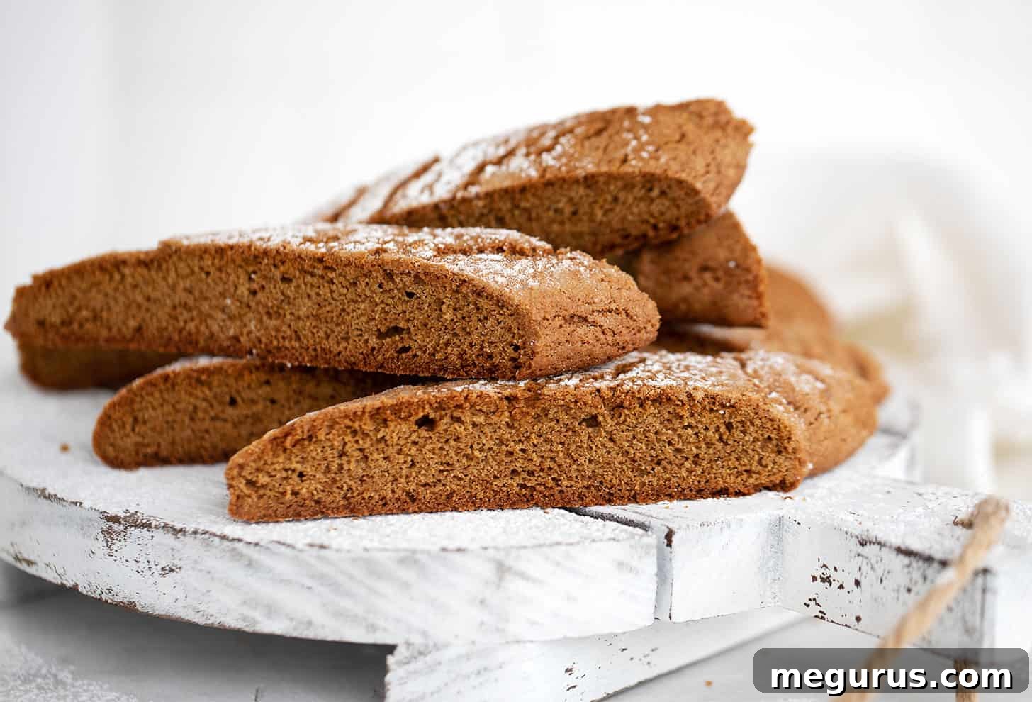 Crispy gingerbread biscotti arranged on a white serving board, ready to be enjoyed or gifted.