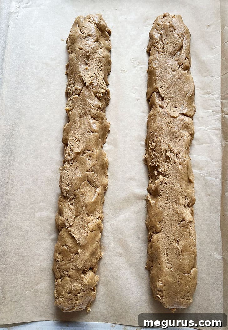 Smooth, evenly shaped gingerbread biscotti dough logs on a baking sheet.
