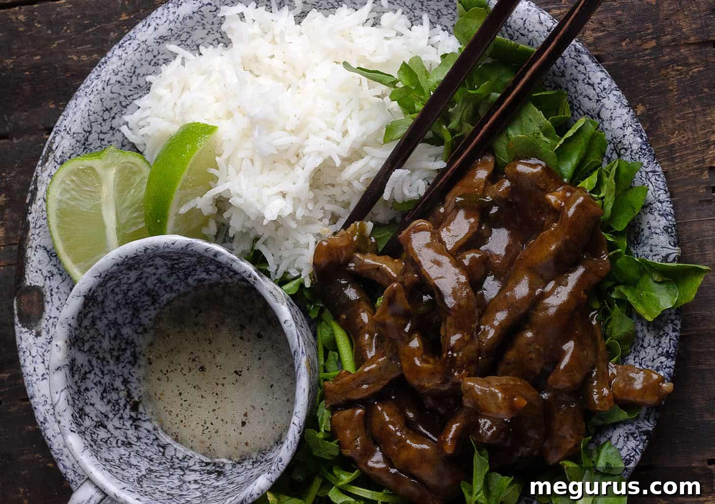 Vietnamese Beef and Watercress Stir Fry (Bo Luc Lac) served on a platter with steamed rice and a side of lime dipping sauce.