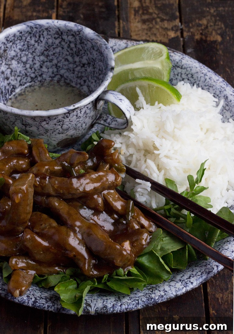 A close-up of Vietnamese Shaking Beef with Watercress (Bo Luc Lac) garnished with lime wedges.