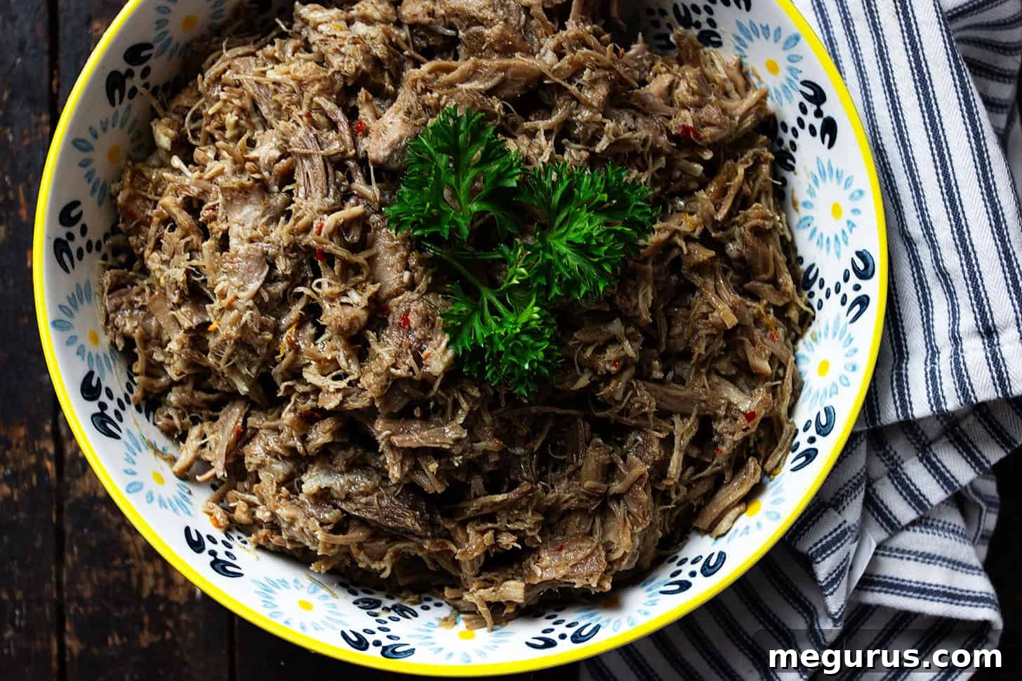 A vibrant bowl of freshly made Slow Cooked Pork Carnitas, garnished with cilantro and lime, ready to be enjoyed in various dishes.