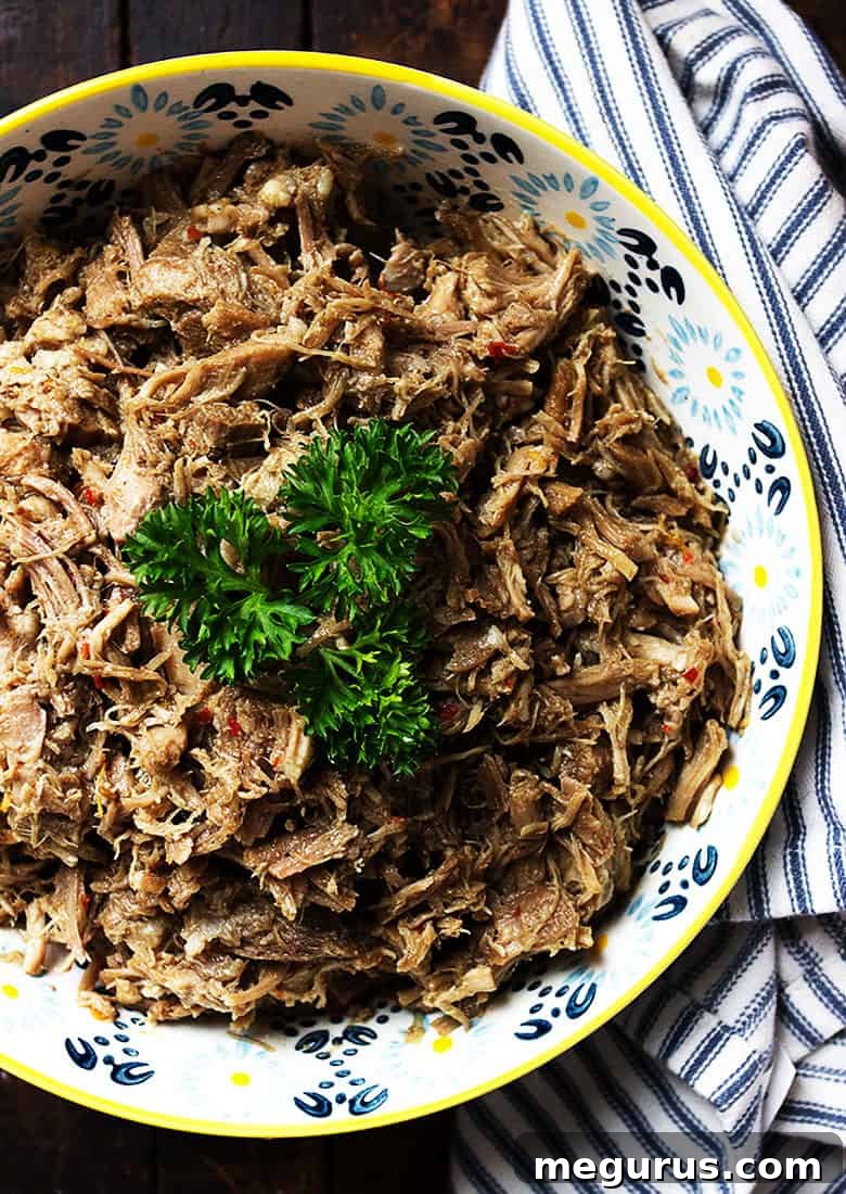 A close-up view of perfectly shredded pork carnitas in a pot, ready for the final crisping step.
