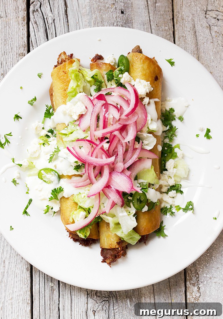 Carnitas Flautas garnished with pickled onions, crema, and cilantro