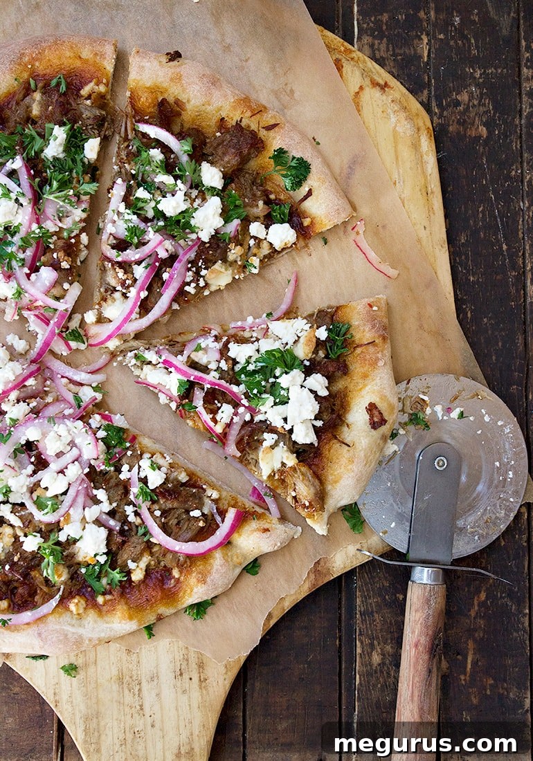 Closeup of a freshly baked Carnitas Pizza garnished with pickled onions and cilantro.
