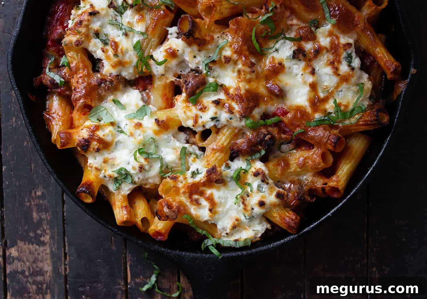 Baked pasta with savory sausage and creamy ricotta in a cast iron skillet, ready to serve.