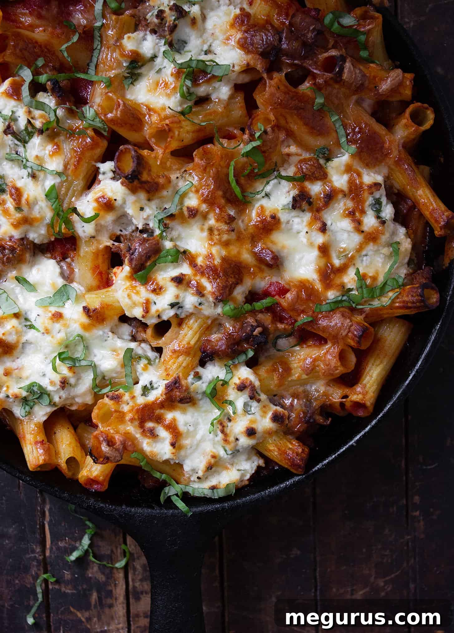 Close-up of baked pasta with sausage and ricotta, showing the creamy ricotta dollops and golden cheese crust.