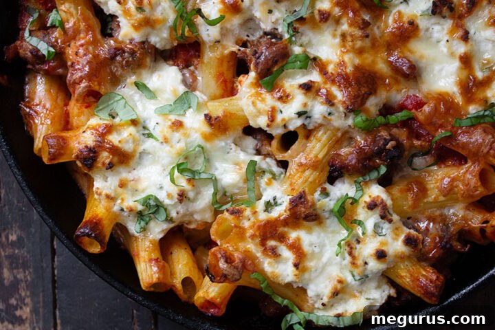 Baked pasta with sausage and ricotta in a cast iron skillet, a full view of the delicious dish.