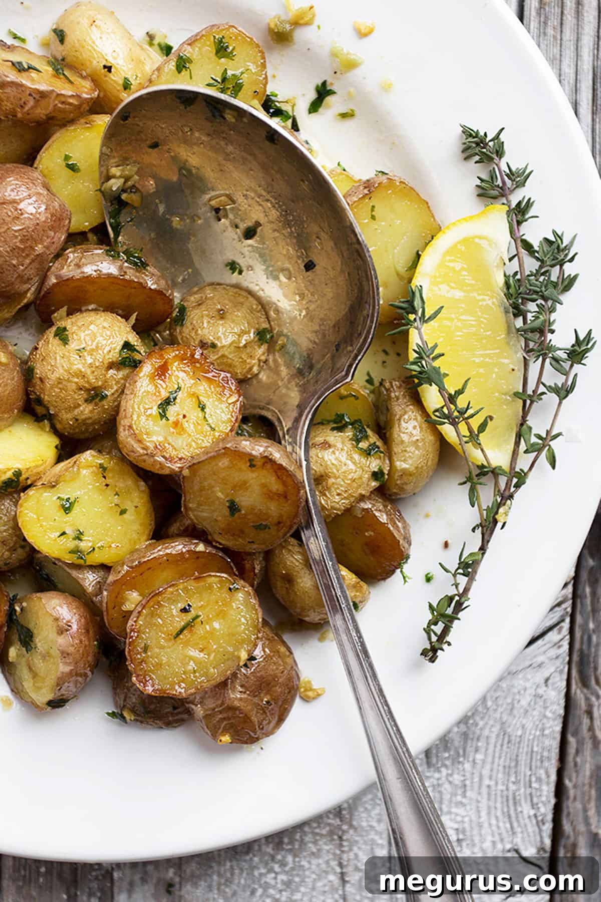Close-up view of golden roasted mini potatoes with minced garlic and green herbs, glistening with butter.