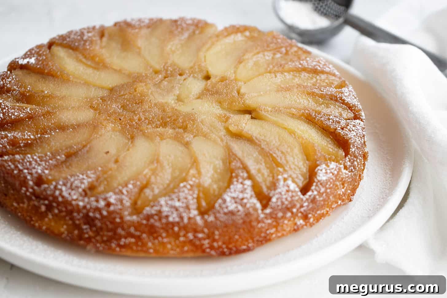 Delicious slice of apple upside down cake on a white plate, showcasing caramelized apples and moist cake
