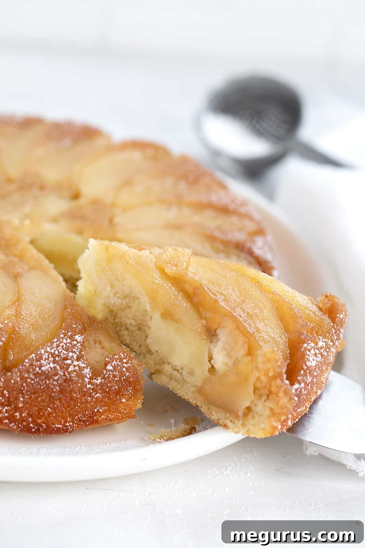 Close-up of a slice of maple apple upside down cake on a white plate