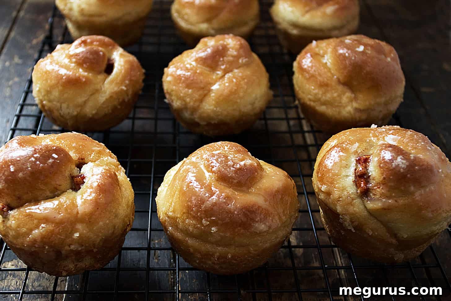 Freshly baked sticky apple cinnamon buns cooling on a wire rack, glistening with maple glaze.