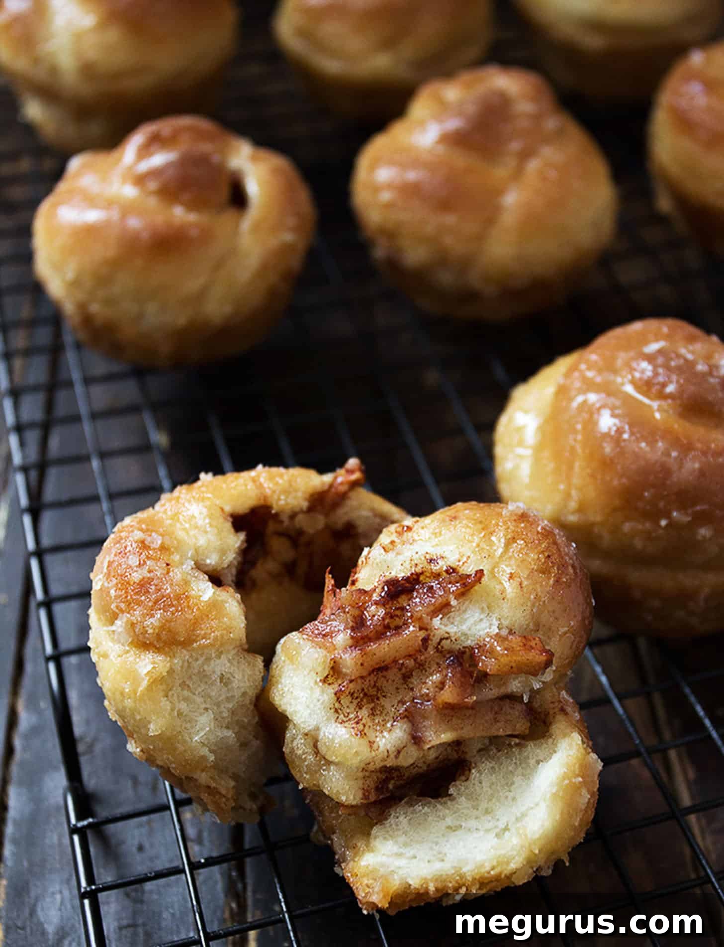 A close-up shot of sticky apple cinnamon buns on a cooling rack, showcasing their golden-brown color and sweet glaze.