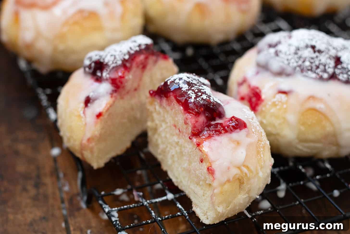 Freshly baked Shrovetide jam buns, sliced open to reveal the fruity filling, cooling on a wire rack.
