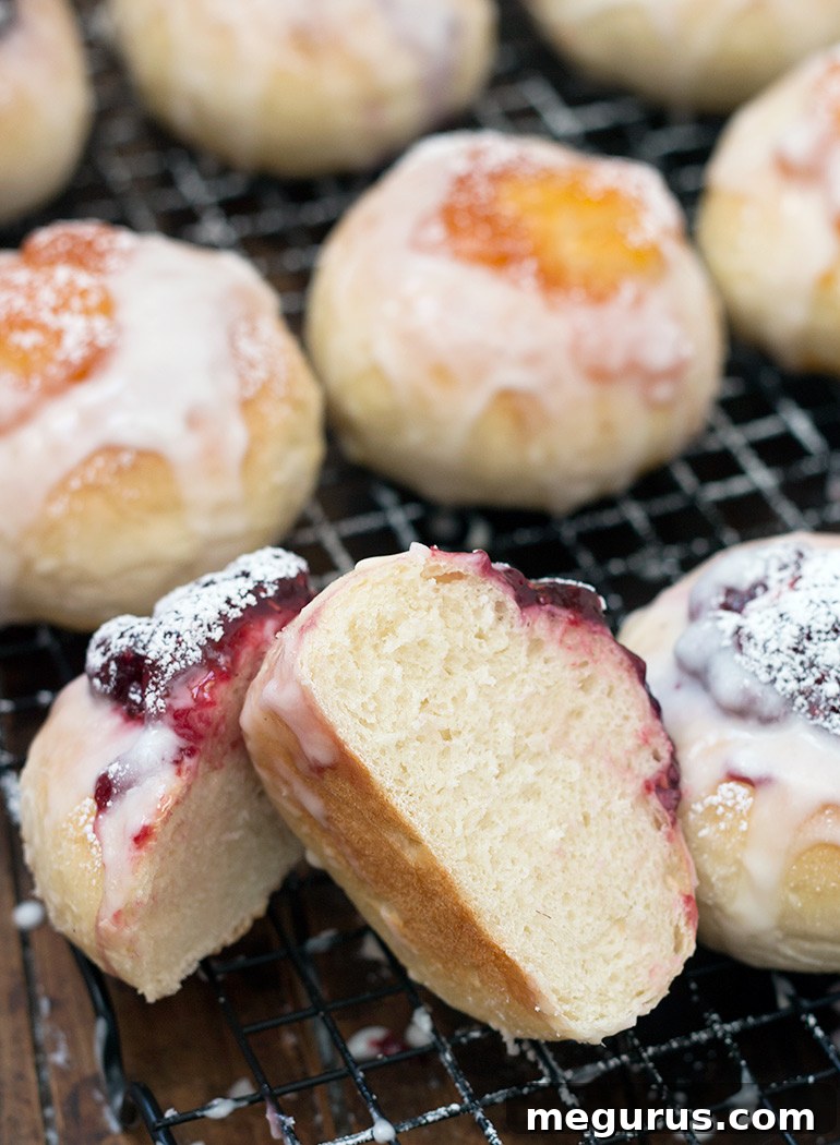 Close-up of freshly baked Shrovetide jam buns, topped with a generous dollop of fruit jam and glistening with sweet glaze.
