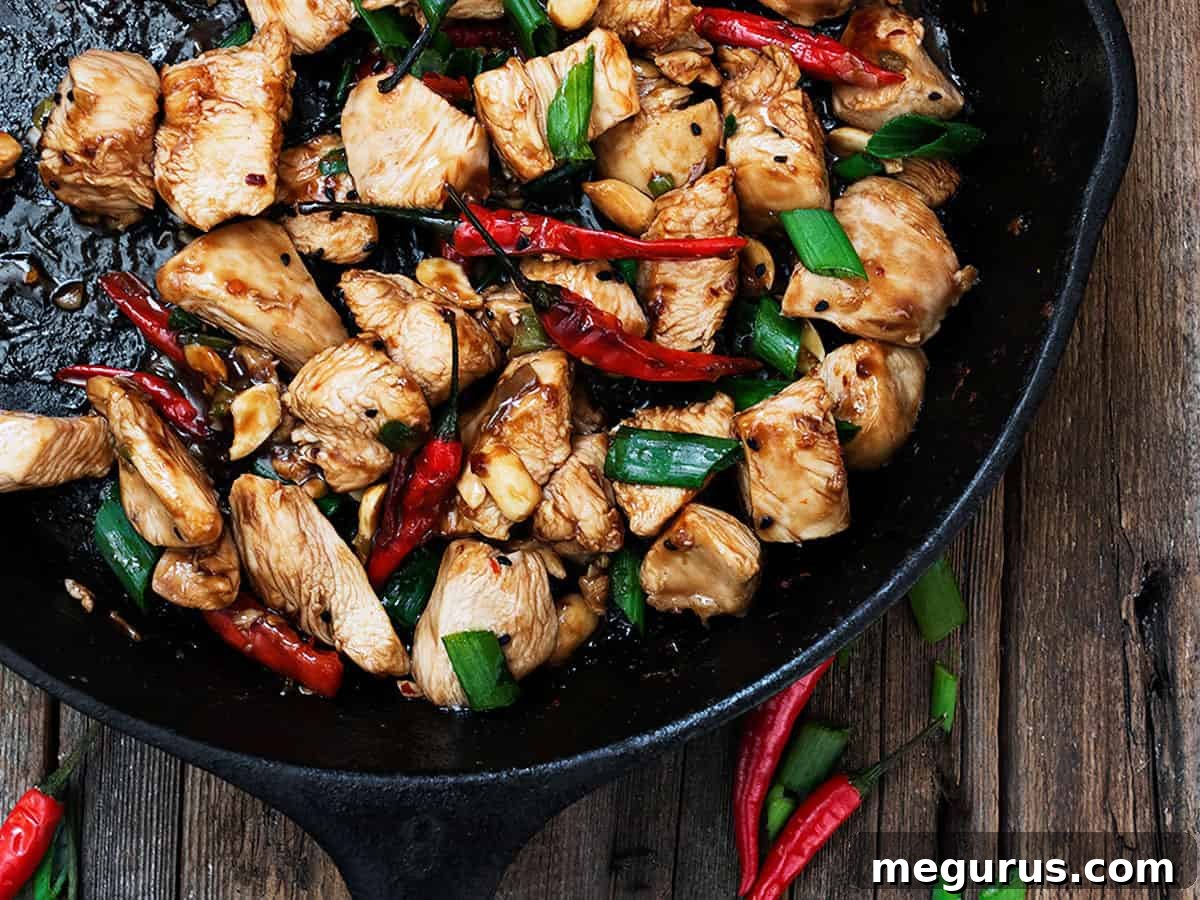 Kung Pao Chicken sizzling in a cast iron skillet with vibrant red peppers