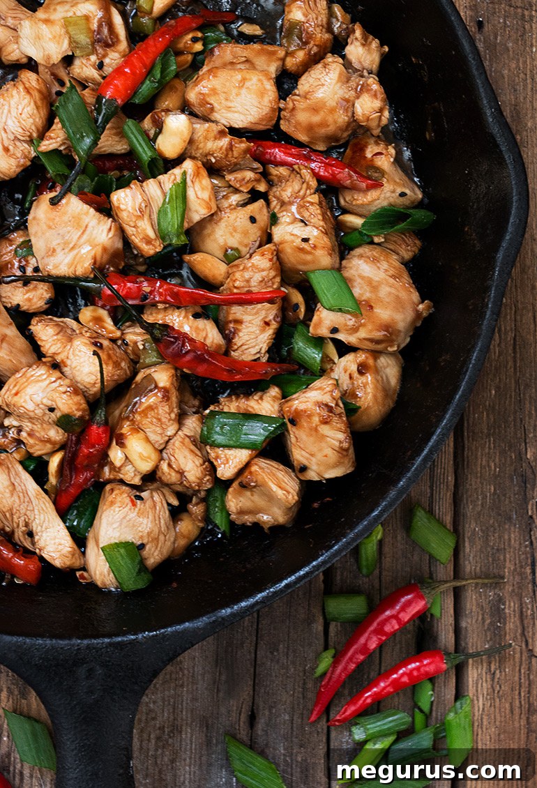 A close-up of a skillet filled with spicy Kung Pao Chicken and peanuts