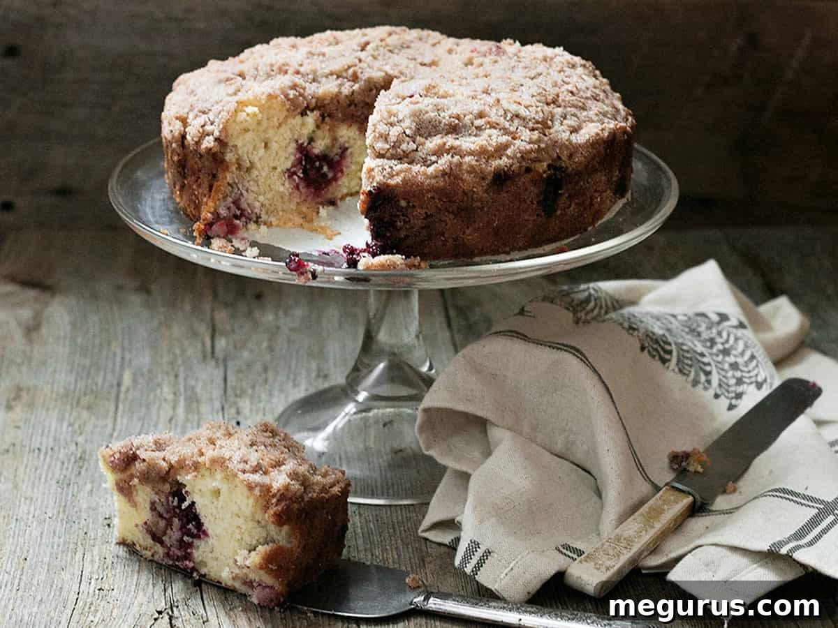berry crumb cake on glass stand sliced open