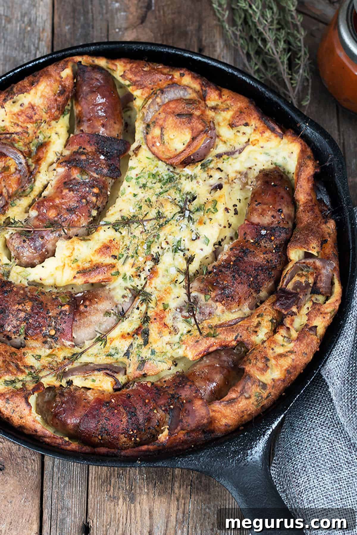 Close-up of golden brown British Toad in the Hole with sausages and onions, steam rising gently