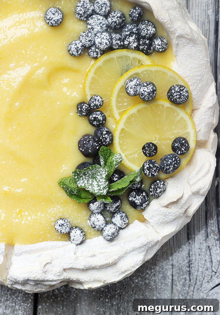 Lemon Curd Pavlova garnished with fresh fruit and powdered sugar.
