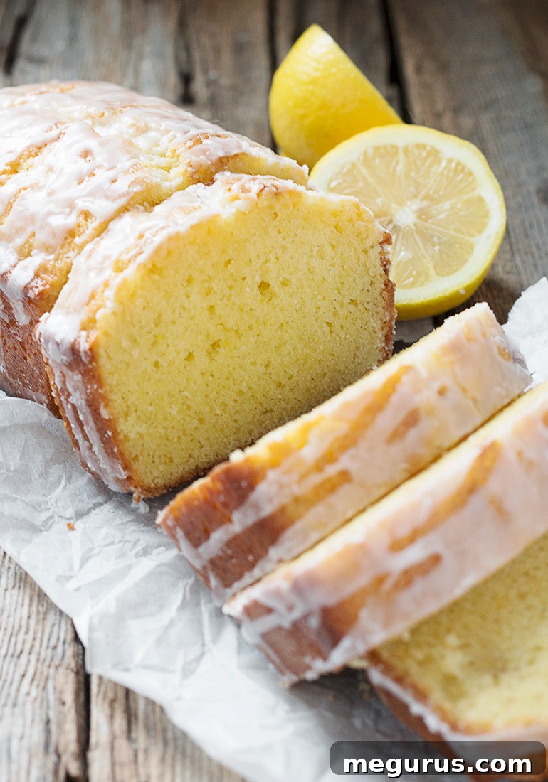 A beautifully sliced Glazed Lemon Pound Cake Loaf on a cooling rack, showcasing its tender crumb and glistening glaze.
