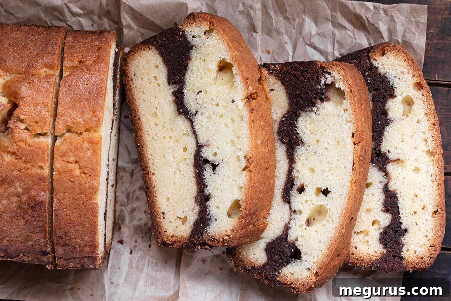 marble pound cake loaf sliced on parchment paper, showcasing the vanilla and brownie swirl
