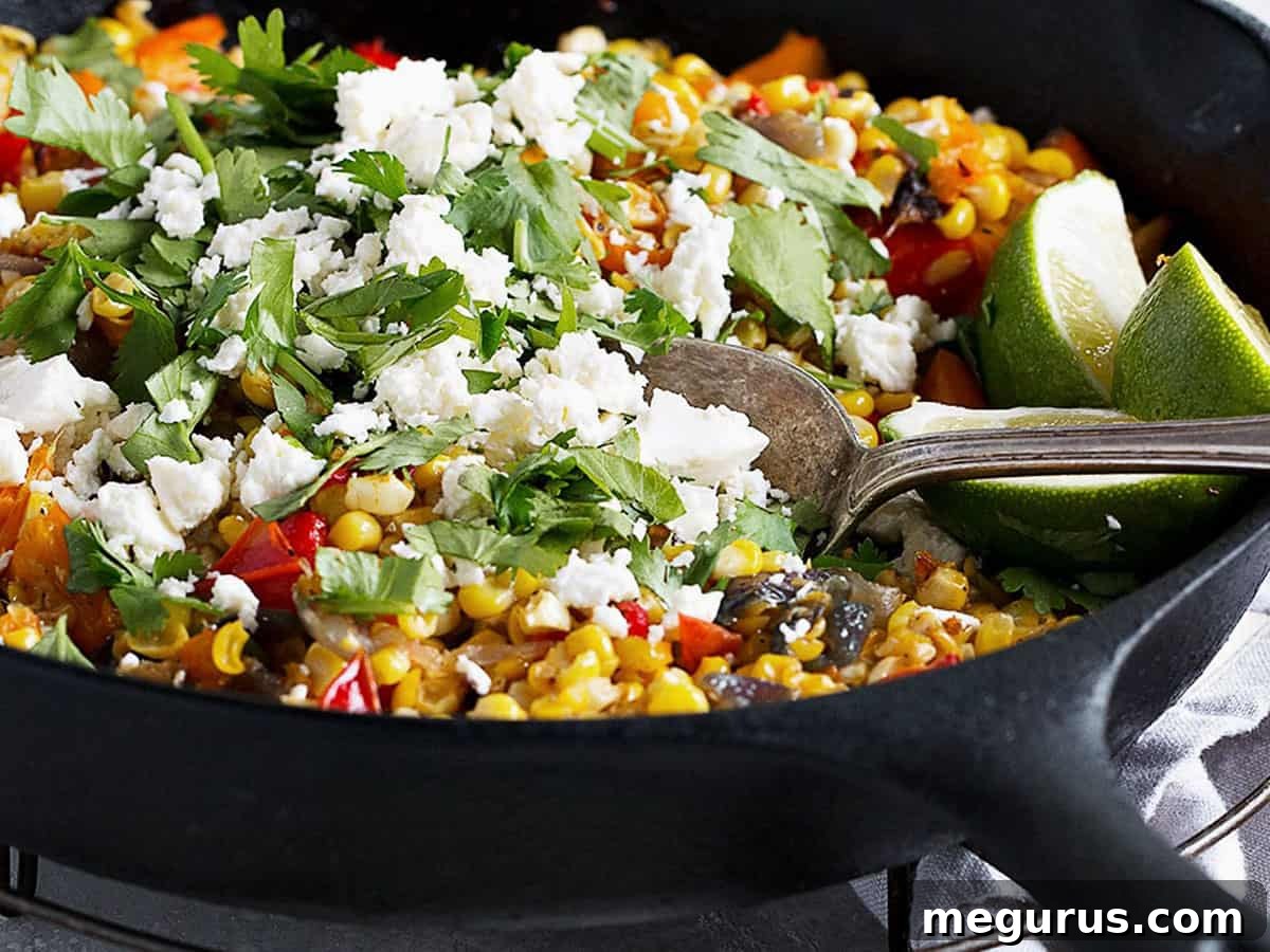 Vibrant skillet roasted corn and bell peppers with crumbled feta cheese and fresh cilantro, ready to serve