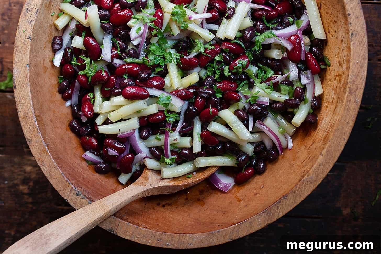 Vibrant Southwest 3 bean salad in a rustic wooden bowl, ready to be served with a spoon.