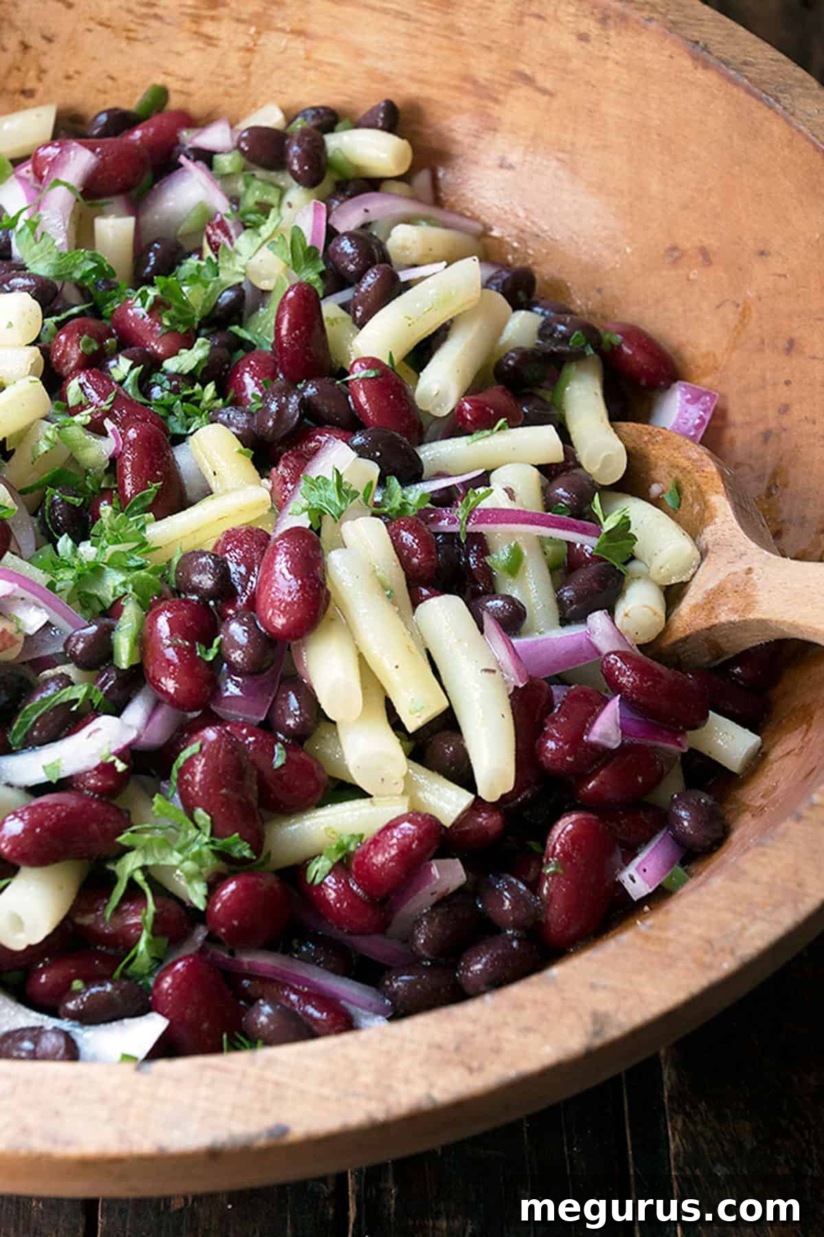 Close-up of bean salad in a rustic wooden bowl, showcasing fresh ingredients.