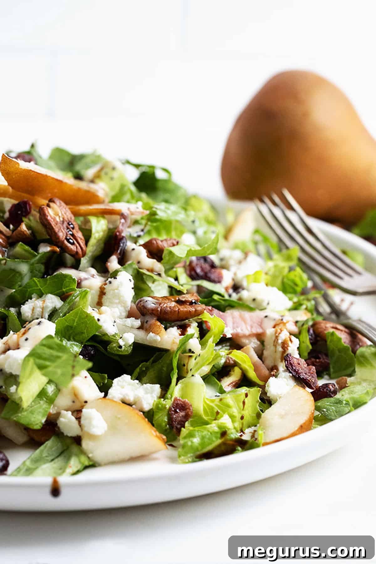 A beautifully presented Fall pear chopped salad on a white plate, showcasing the vibrant colors and textures of the ingredients.