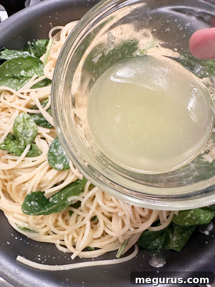 Fresh lemon juice being drizzled over the pasta and sauce in the skillet.