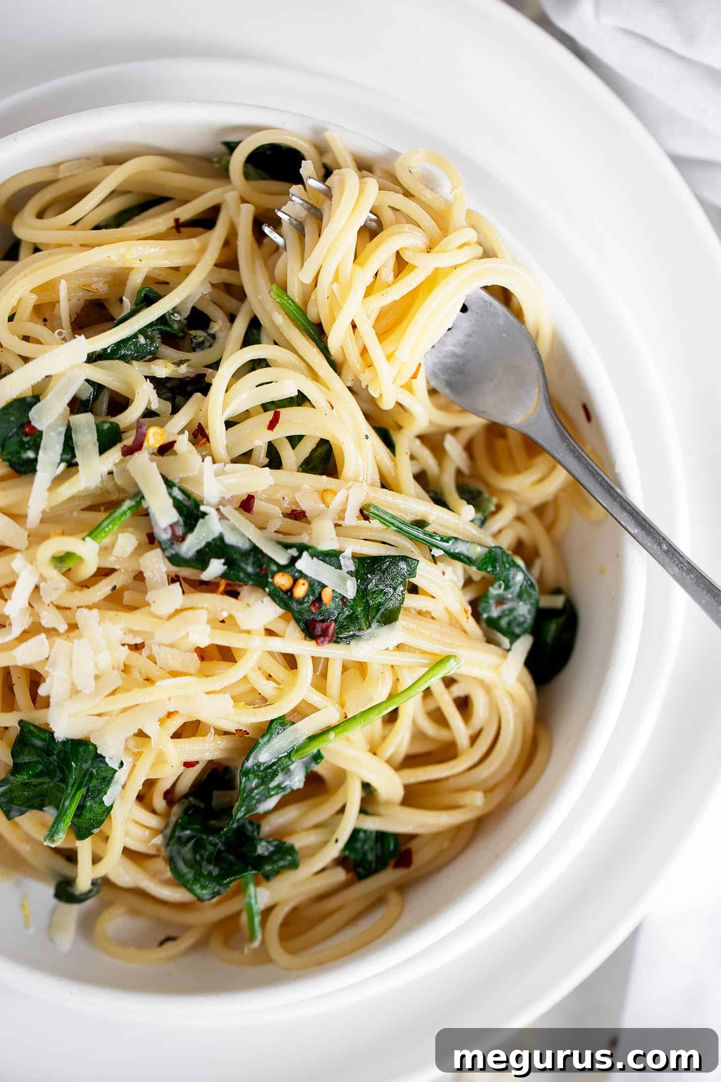 A close-up of lemon spinach pasta with a fork, emphasizing its creamy texture.