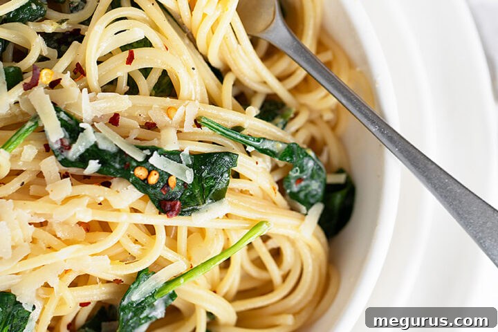 Lemon spinach pasta in bowl with fork, ready to be eaten.