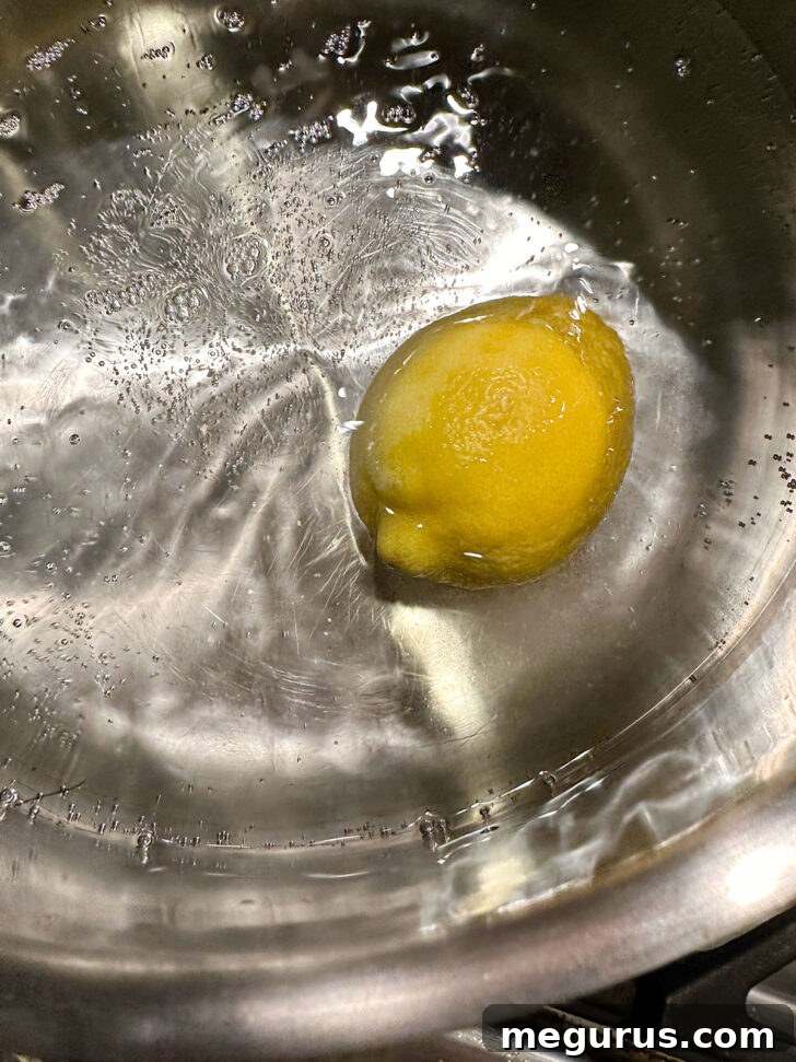 A whole lemon being boiled in a large pot of water on the stove.