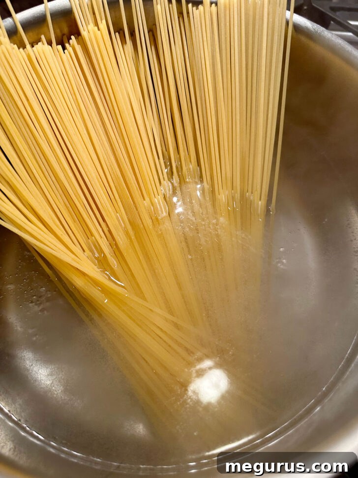 Dried spaghetti being carefully added to the pot of boiling, salted water.