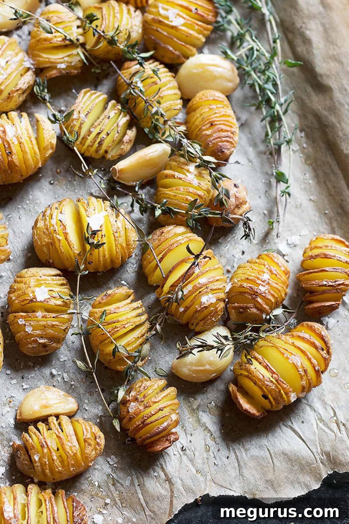 A close-up of perfectly roasted Hasselback mini potatoes on a baking sheet lined with parchment paper.