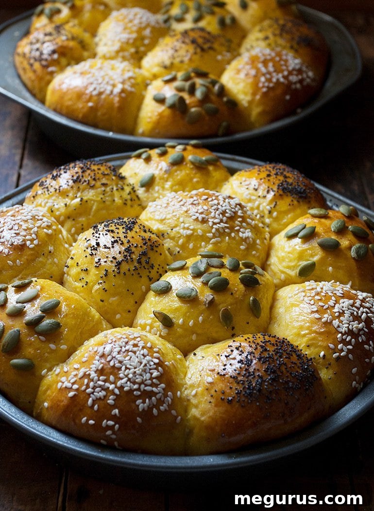 A close-up of a platter of baked Honey Pumpkin Dinner Rolls, showcasing their golden crust and fluffy texture.