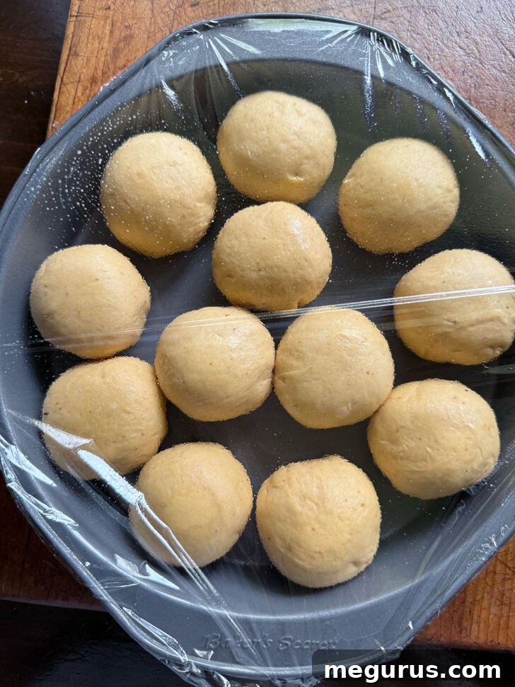 Arranged dough balls placed in a greased baking pan, ready for the second rise.