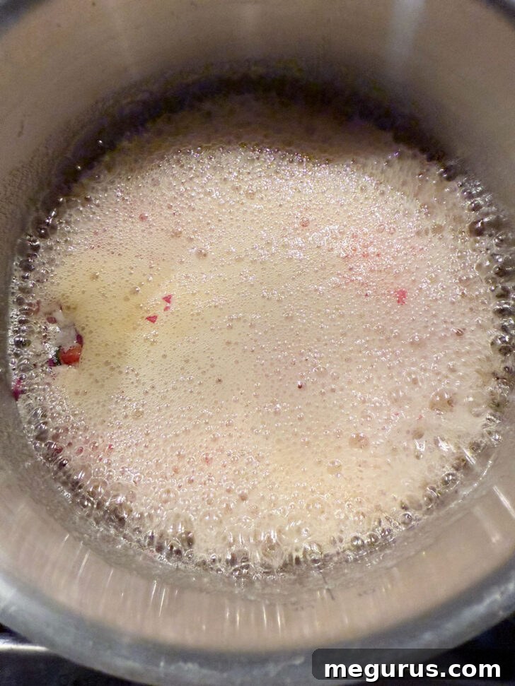 Jelly mixture at a full, vigorous rolling boil, indicating it's reaching setting point.
