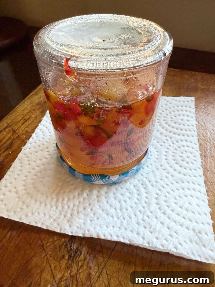 Freshly made apricot jalapeño jelly inverted in jars, distributing the fruit and pepper pieces evenly.