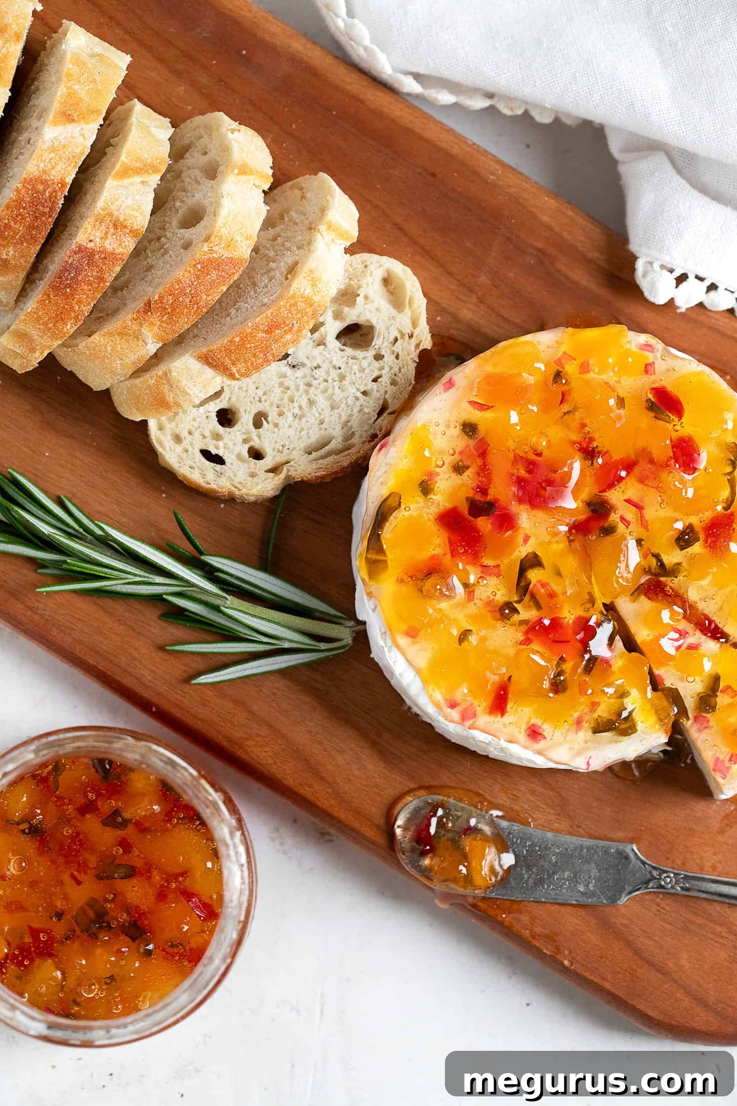 Close-up of Apricot Jalapeño Jelly served on a rustic wooden board with crackers and soft cheese.