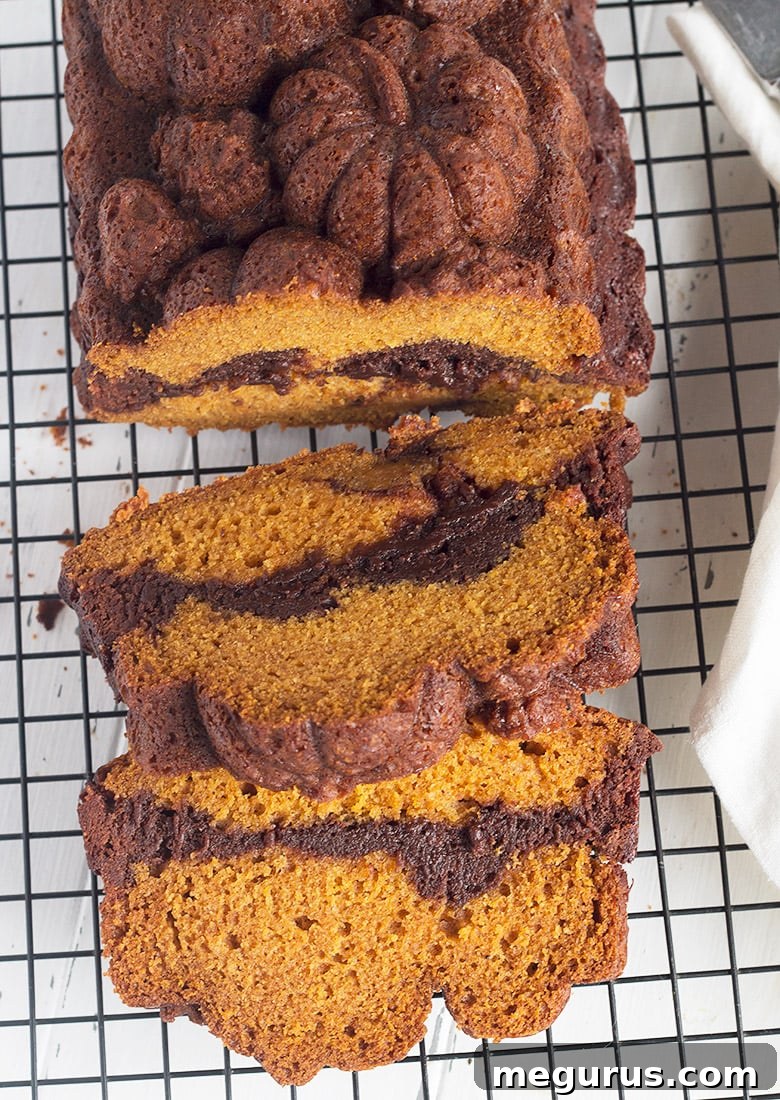 A freshly baked pumpkin chocolate swirl bread resting on a cooling rack, showcasing its golden-brown crust.
